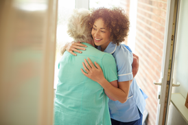 Home care worker hugs her patient at the front door.